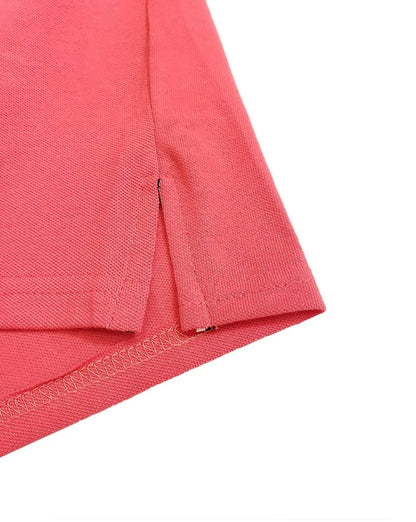 Primer plano del acabado inferior de un polo Dubrovnik color coral, mostrando la abertura lateral con refuerzo interno y doble costura de seguridad en el dobladillo