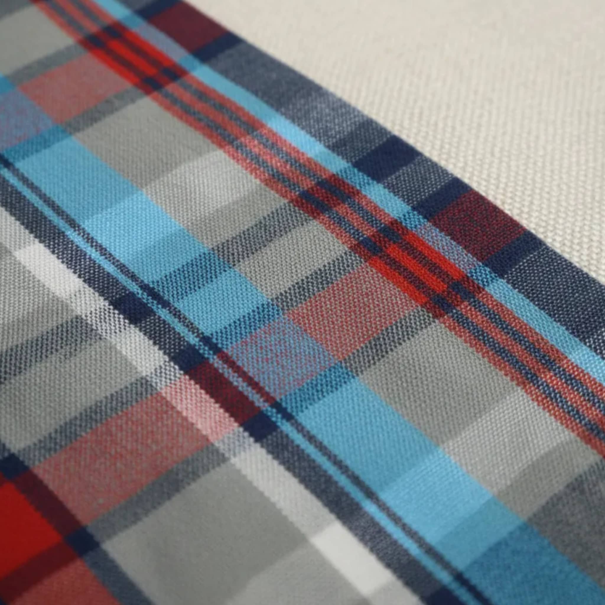 Primer plano del tejido de algodón con estampado de cuadros en azul celeste, gris y líneas rojas de una camisa Dubrovnik