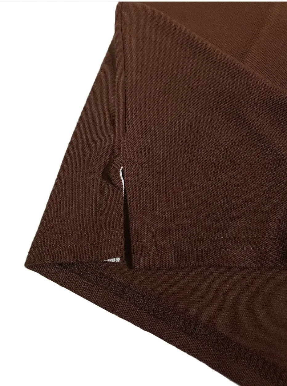 Primer plano del acabado inferior de un polo Dubrovnik color café chocolate, destacando la abertura lateral con cinta de refuerzo interna en color marfil y doble costura