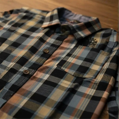 Vista en ángulo de camisa de cuadros para niño en colores gris, azul y naranja con enfoque en el bolsillo y cuello