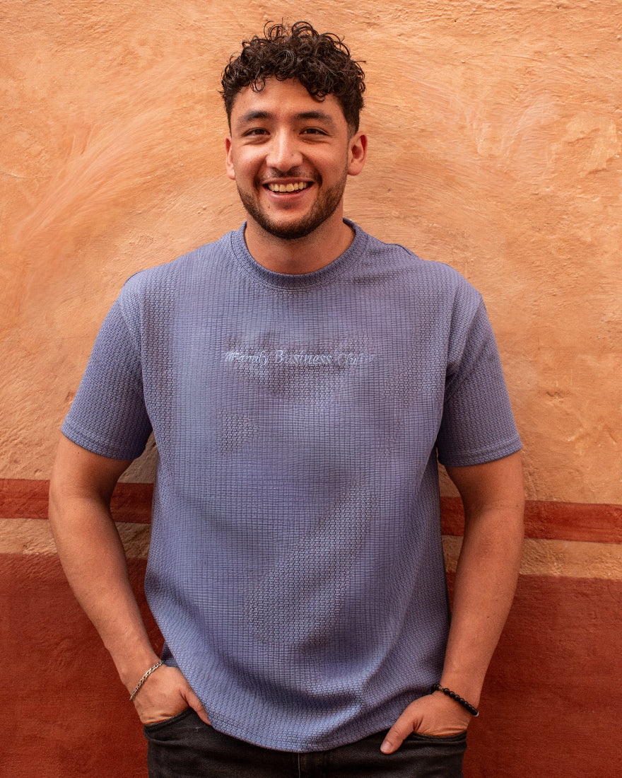 Hombre sonriente con camiseta texturizada en color azul lavanda y gráfico frontal 