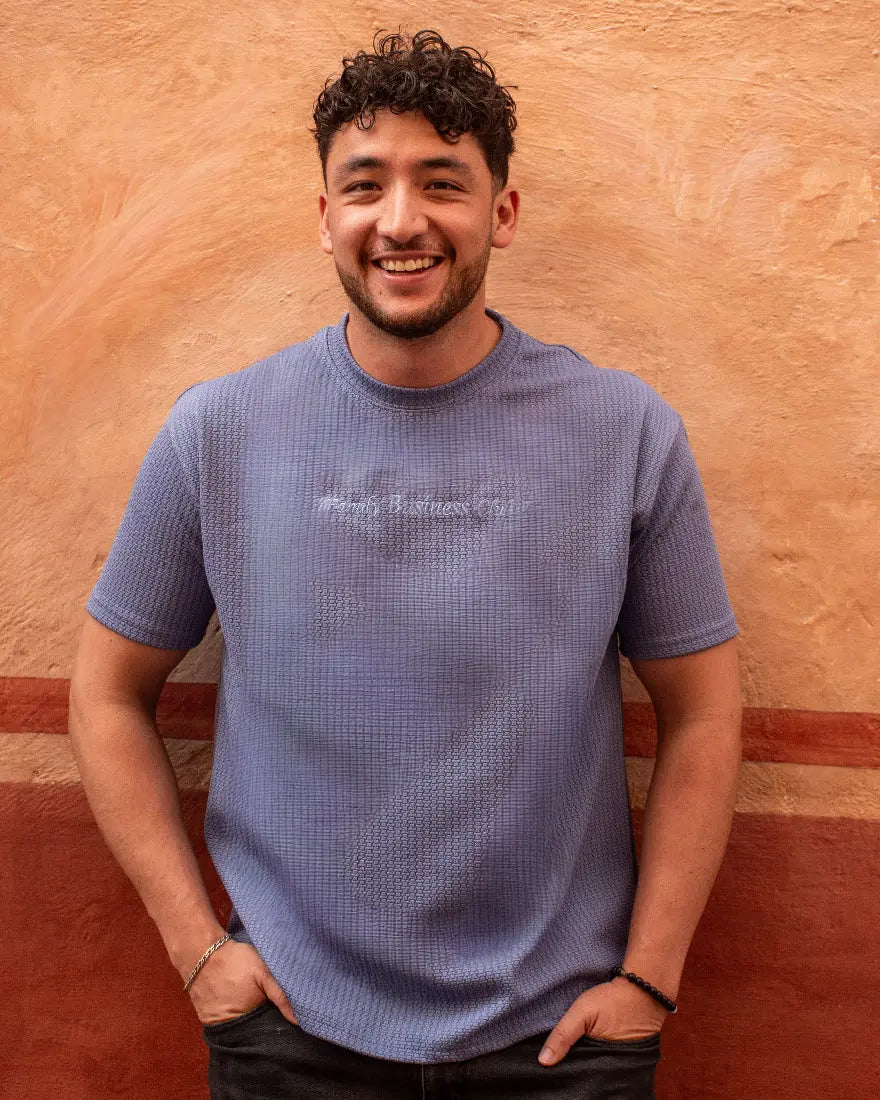 Hombre sonriente con camiseta texturizada en color azul lavanda y gráfico frontal "Trendy Business Club" de la marca Dubrovnik