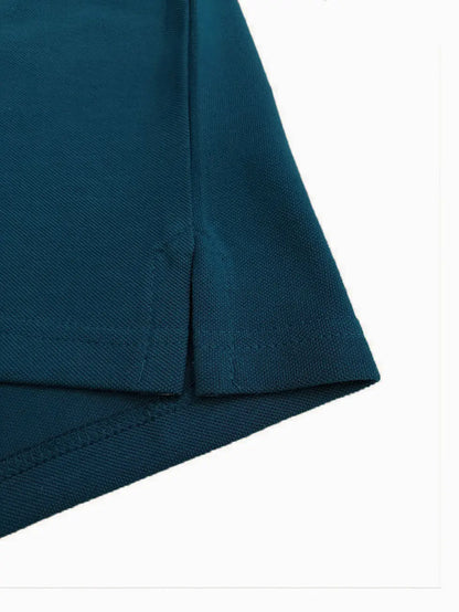 Primer plano del detalle de la costura y abertura lateral de un polo infantil en color azul petróleo, resaltando la textura del tejido piqué de alta calidad de la marca Dubrovnik
