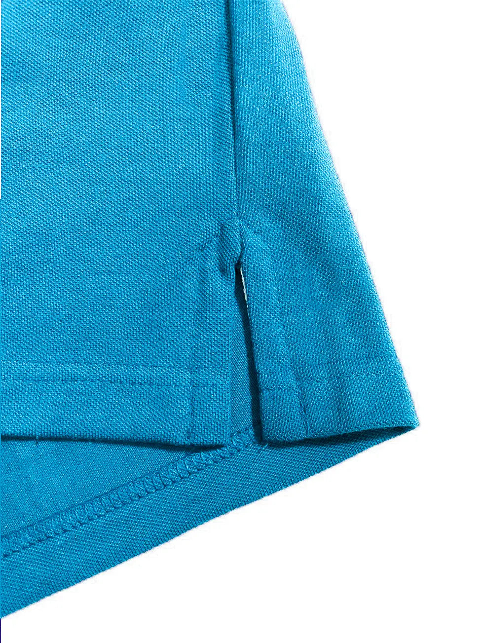 Primer plano del detalle de la costura y la abertura lateral inferior de un polo infantil en color azul real, resaltando la calidad del tejido y el acabado de la marca Dubrovnik