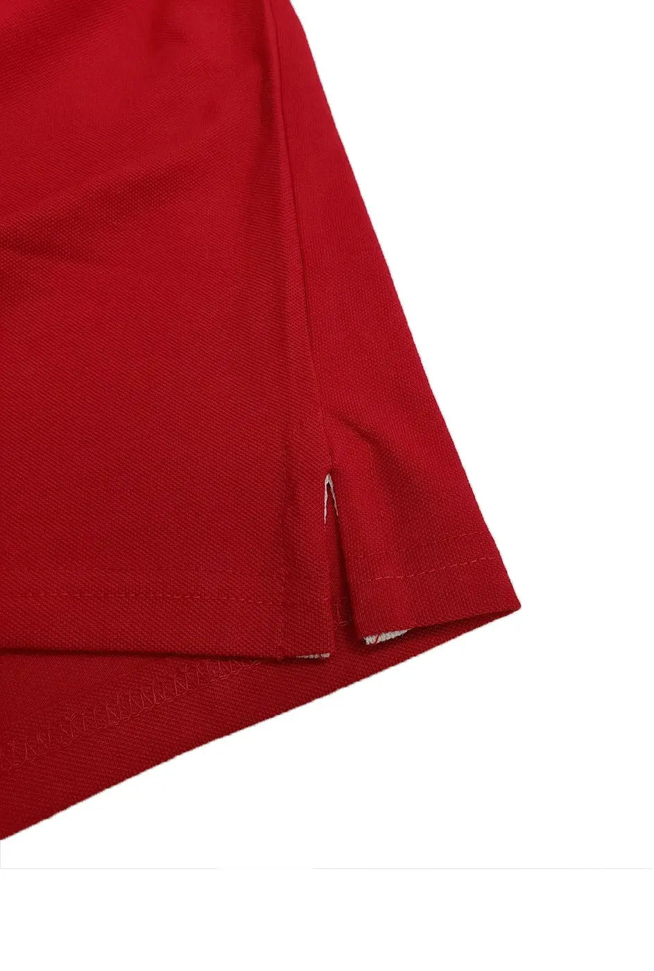 Primer plano del detalle de la costura y abertura lateral inferior de un polo color rojo, resaltando el acabado de calidad y la textura del tejido de la marca Dubrovnik