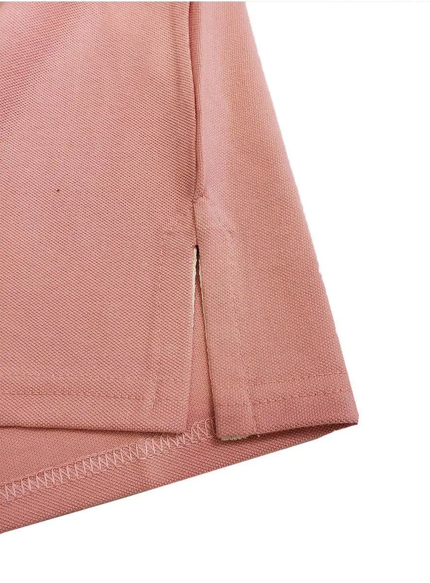 Primer plano del detalle de la costura y abertura lateral de un polo infantil en color rosa pastel, mostrando el acabado de la prenda y la textura del tejido piqué de la marca Dubrovnik