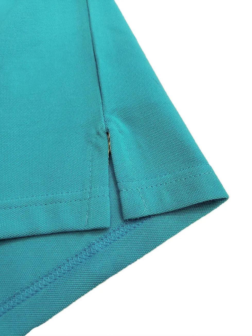 Primer plano del acabado de la costura y abertura lateral inferior de un polo color turquesa, resaltando la textura del tejido piqué de la marca Dubrovnik
