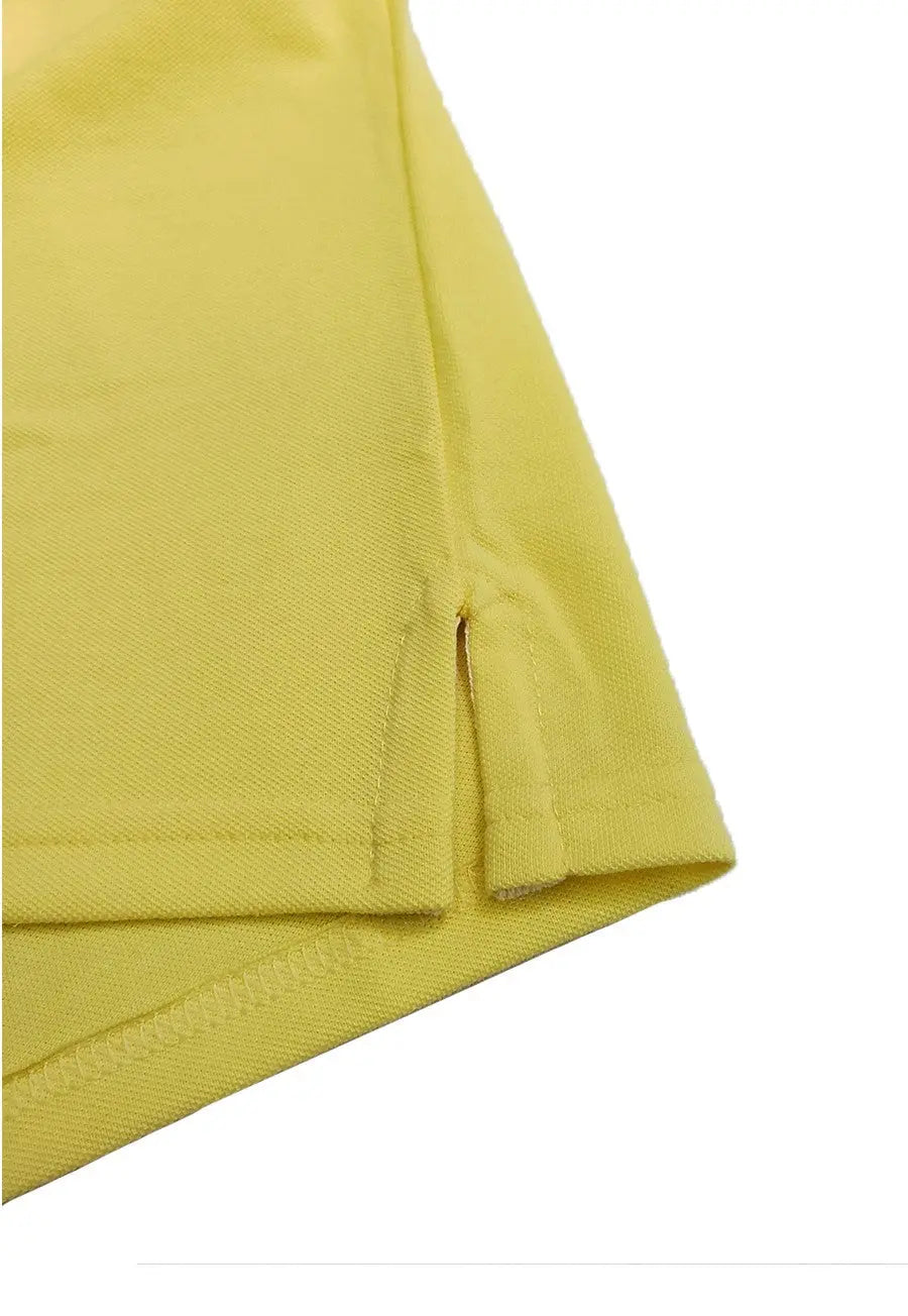 Primer plano del detalle de la costura y abertura lateral inferior de un polo infantil en color verde lima, mostrando la calidad del tejido piqué de la marca Dubrovnik