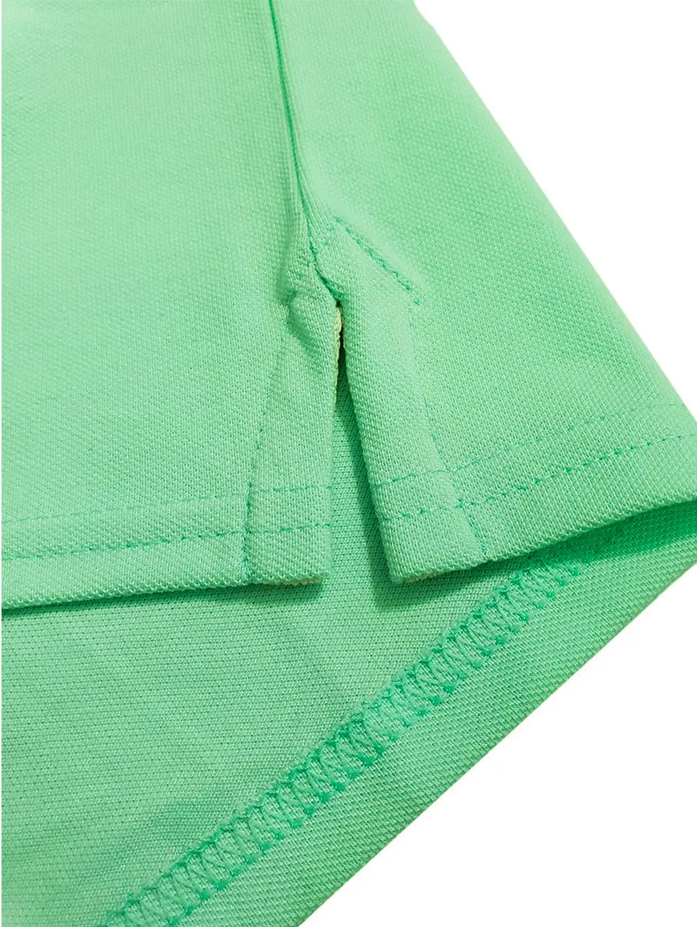 Primer plano del detalle de la costura y abertura lateral de un polo infantil en color verde menta, resaltando la textura del tejido piqué y la calidad del acabado de Dubrovnik