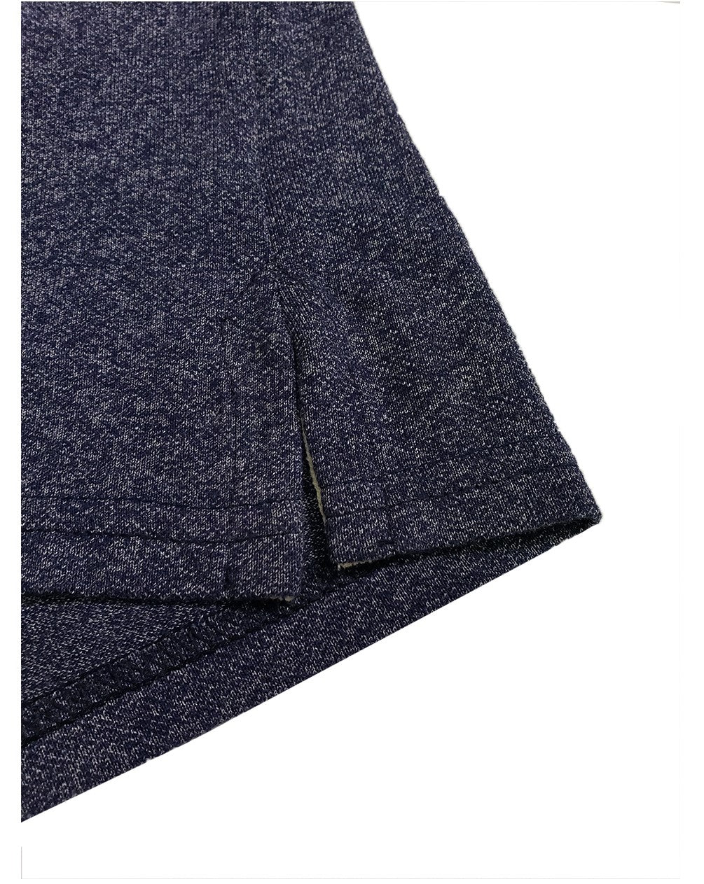 Primer plano del acabado inferior de un polo Dubrovnik azul marino jaspeado, mostrando la abertura lateral con refuerzo interno en tono crema y doble costura