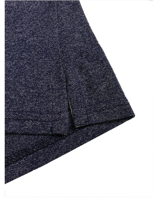 Primer plano del acabado inferior de un polo Dubrovnik azul marino jaspeado, mostrando la abertura lateral con refuerzo interno en tono crema y doble costura