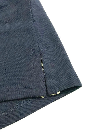 Primer plano del acabado inferior de un polo Dubrovnik color azul petróleo, mostrando la abertura lateral con cinta de refuerzo interna en tono contraste claro