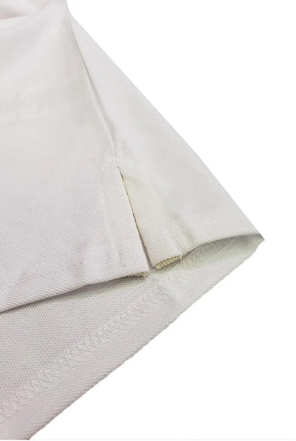 Primer plano del acabado inferior de un polo Dubrovnik color blanco, destacando la abertura lateral reforzada y la calidad de la doble costura en el dobladillo
