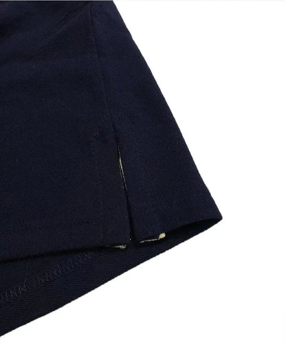 Primer plano del acabado inferior de un polo Dubrovnik negro, mostrando la abertura lateral con cinta de refuerzo interna en color blanco y doble costura de seguridad