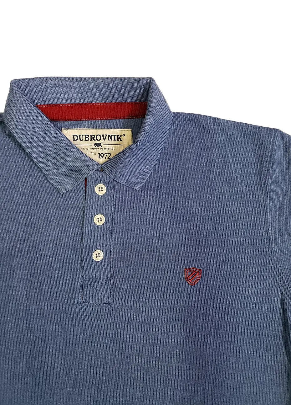 Primer plano de polo Dubrovnik azul jaspe mostrando el contraste en rojo tinto de la carterita interna, botones marfil y el escudo bordado con alta precisión