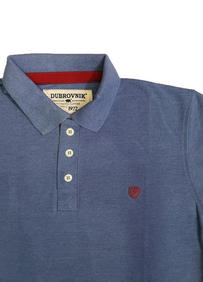 Primer plano de polo Dubrovnik azul jaspe mostrando el contraste en rojo tinto de la carterita interna, botones marfil y el escudo bordado con alta precisión