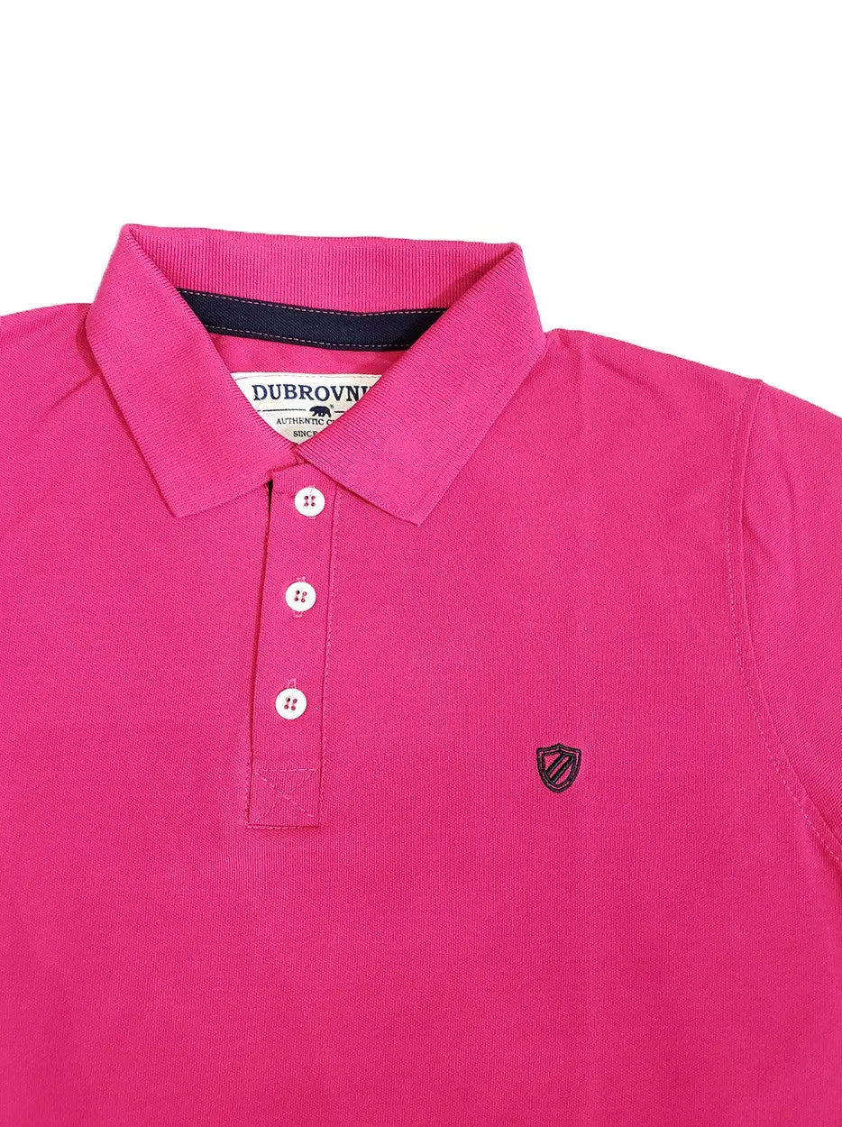 Primer plano de polo Dubrovnik color rosa fucsia vibrante, mostrando el contraste azul marino en la cinta interna del cuello, botones reforzados y escudo bordado de alta precisión