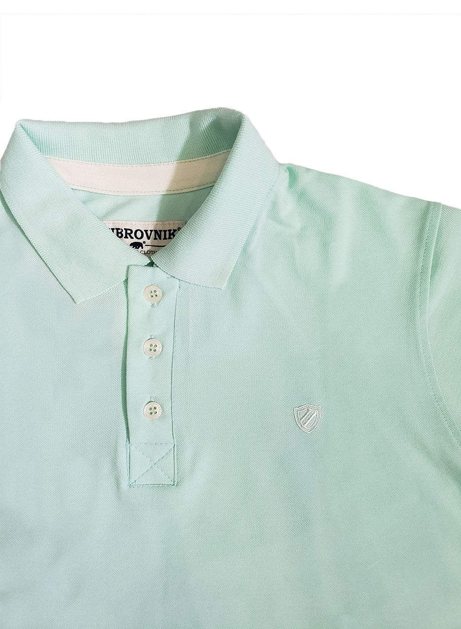 Primer plano de polo Dubrovnik color verde menta, mostrando el tapacosturas interno en contraste, botones reforzados y el escudo bordado con alta precisión