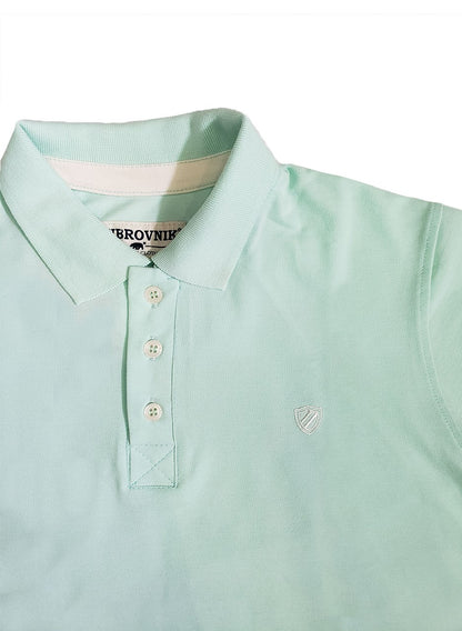 Primer plano de polo Dubrovnik color verde menta, mostrando el tapacosturas interno en contraste, botones reforzados y el escudo bordado con alta precisión