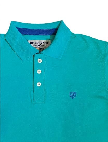 Primer plano del cuello de un polo color turquesa de la marca Dubrovnik, mostrando la etiqueta interna, la botonera con botones blancos y el pequeño logotipo de escudo bordado en el pecho