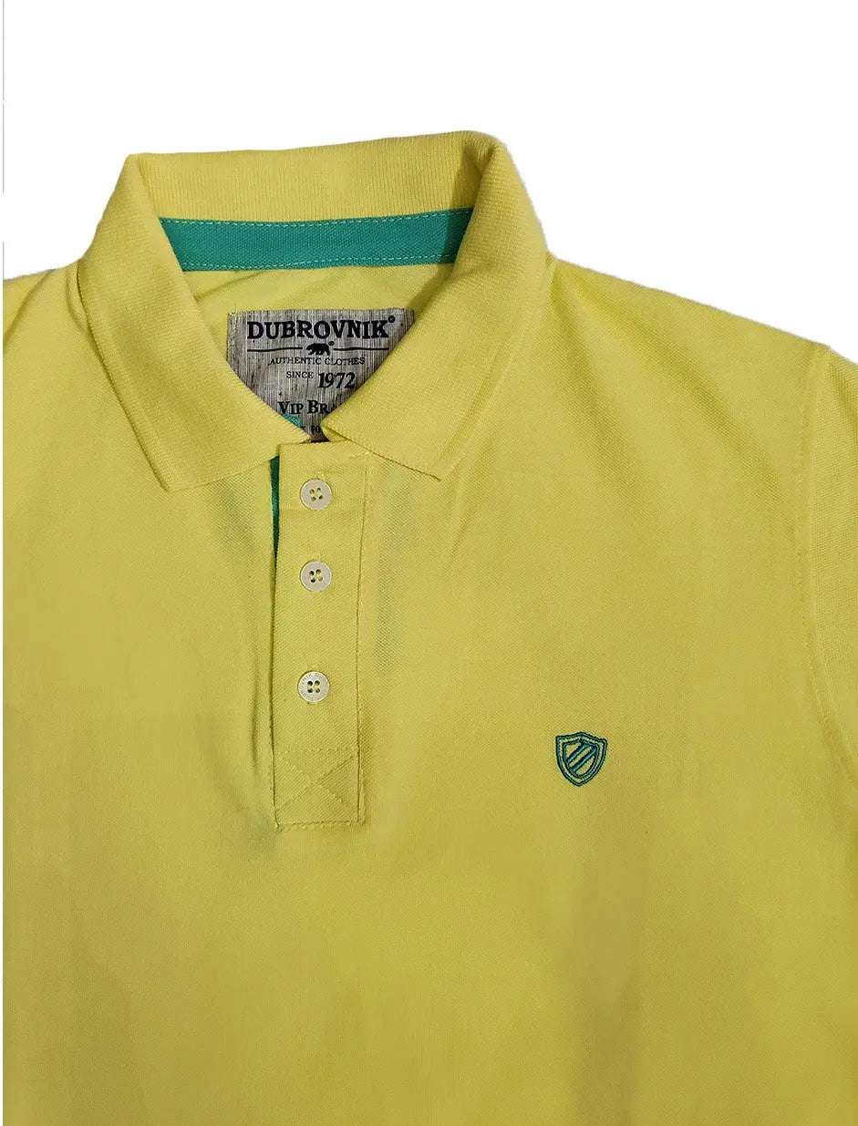 Primer plano del cuello de un polo color verde lima de la marca Dubrovnik, mostrando el contraste turquesa en la tira interna del cuello, botones blancos y el logotipo de escudo bordado en verde sobre el pecho