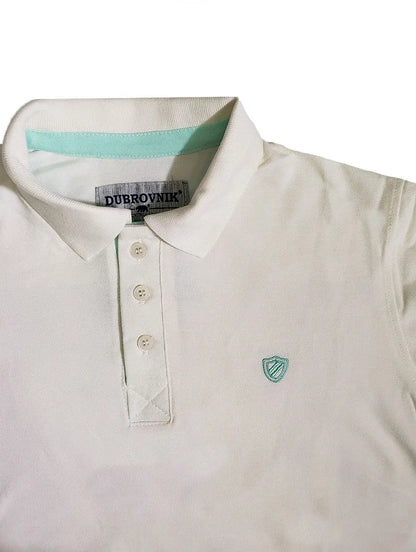 Primer plano de polo Dubrovnik blanco con detalle de cinta interna en color aqua, botones perlados y escudo bordado a tono en el pecho
