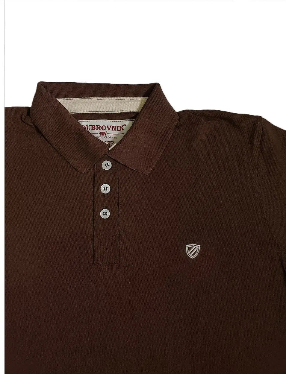 Primer plano de polo Dubrovnik color café chocolate, mostrando la cinta interna en tono marfil, botones perlados y el escudo bordado a tono en el pecho