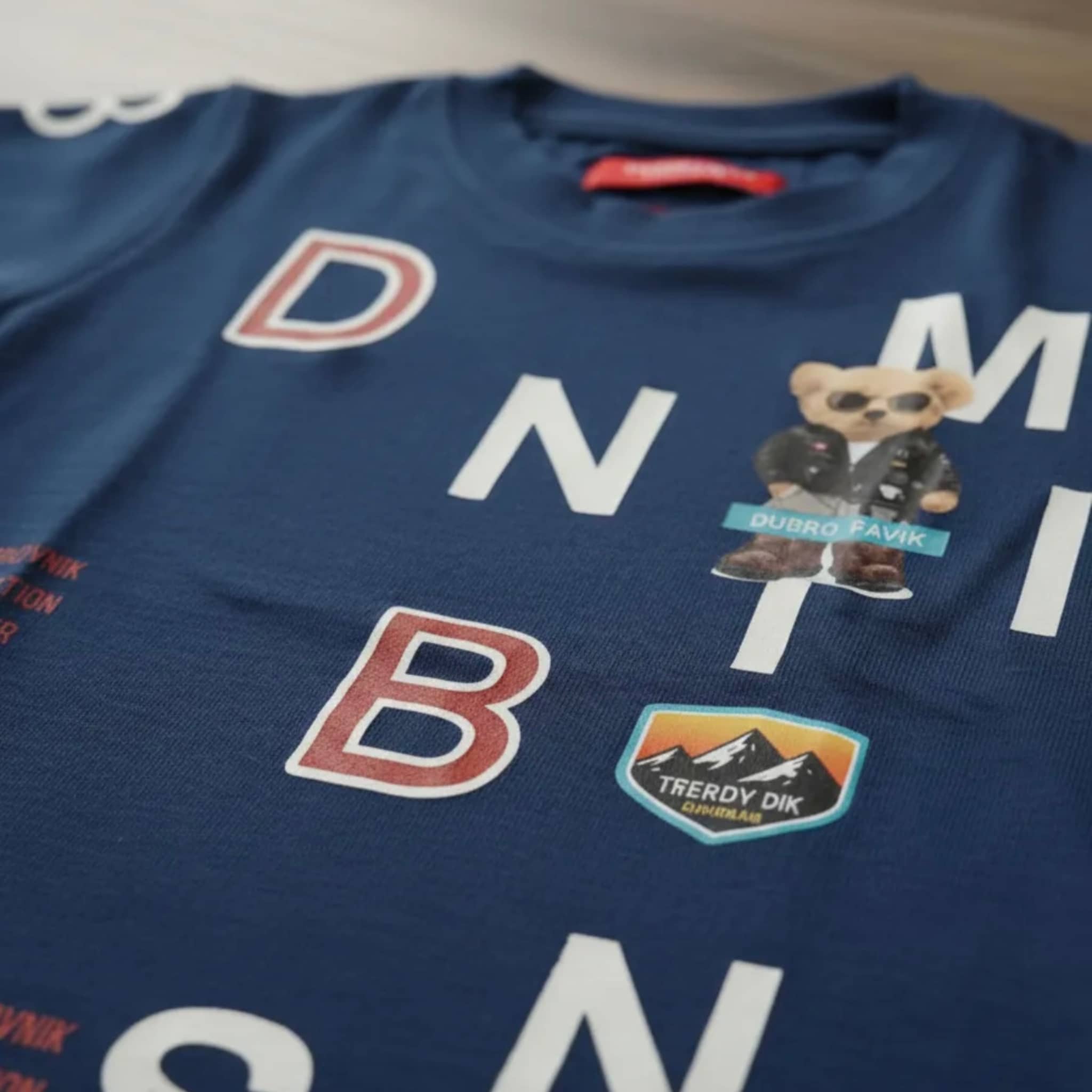 Primer plano de camiseta azul marino para niño con parches de oso con gafas, montañas 