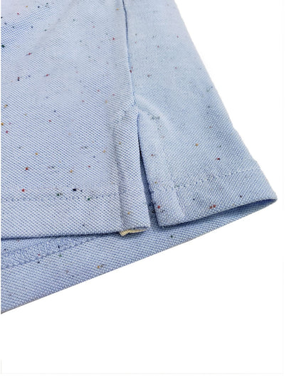 Primer plano del dobladillo inferior de un polo Dubrovnik azul cielo con efecto jaspeado, mostrando la abertura lateral reforzada y la textura del tejido de piqué