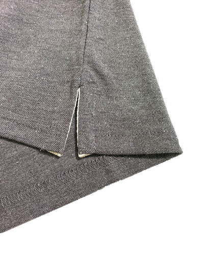 Primer plano del dobladillo inferior de un polo Dubrovnik gris oxford, mostrando la abertura lateral con cinta de refuerzo interna clara y costura de precisión