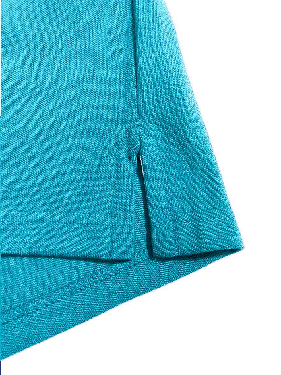 Primer plano del acabado inferior de un polo Dubrovnik color azul turquesa, mostrando la apertura lateral reforzada y la textura del tejido piqué premium