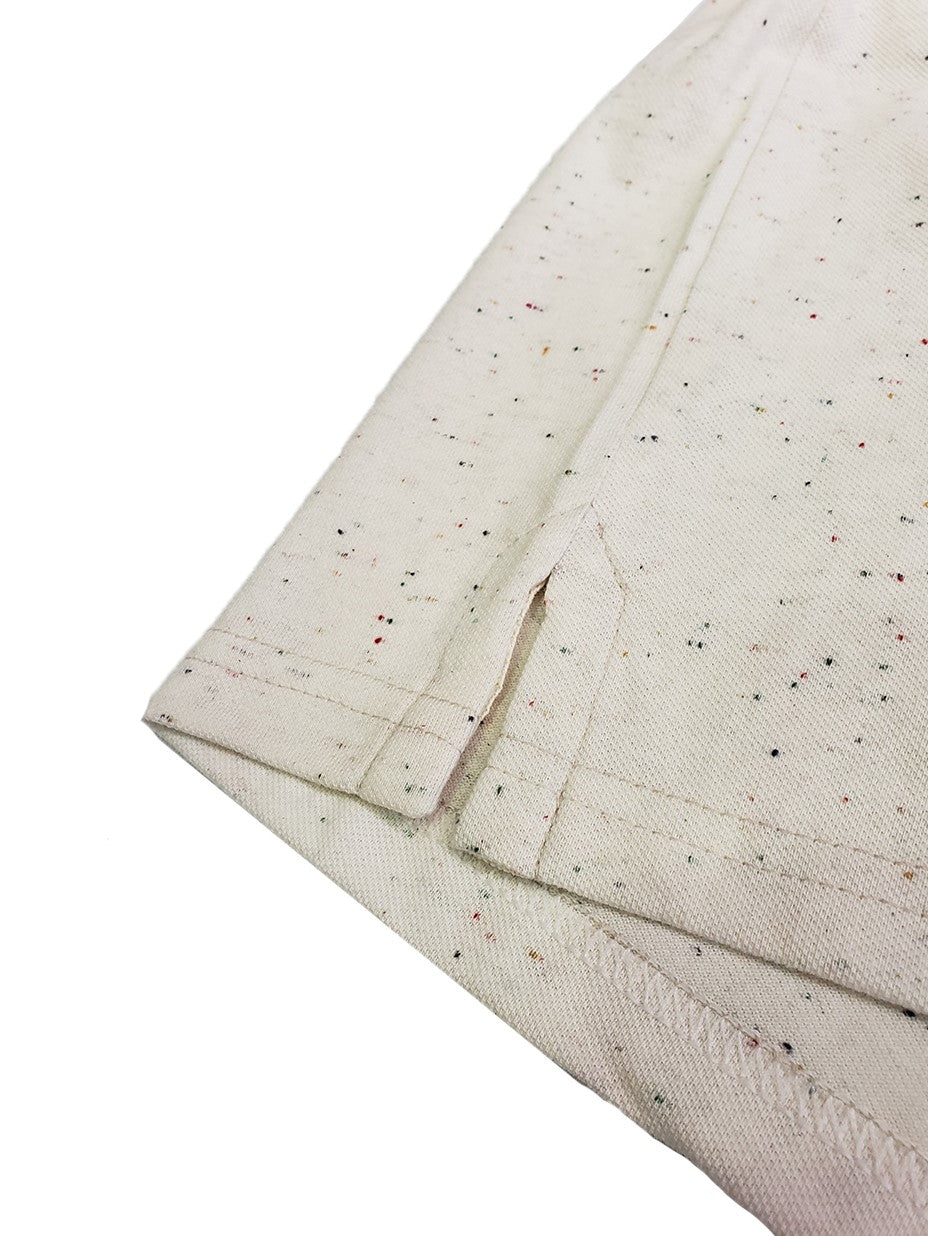 Primer plano del acabado inferior de un polo Dubrovnik beige con efecto jaspeado multicolor, destacando la abertura lateral reforzada y la costura de seguridad