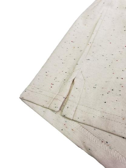 Primer plano del acabado inferior de un polo Dubrovnik beige con efecto jaspeado multicolor, destacando la abertura lateral reforzada y la costura de seguridad