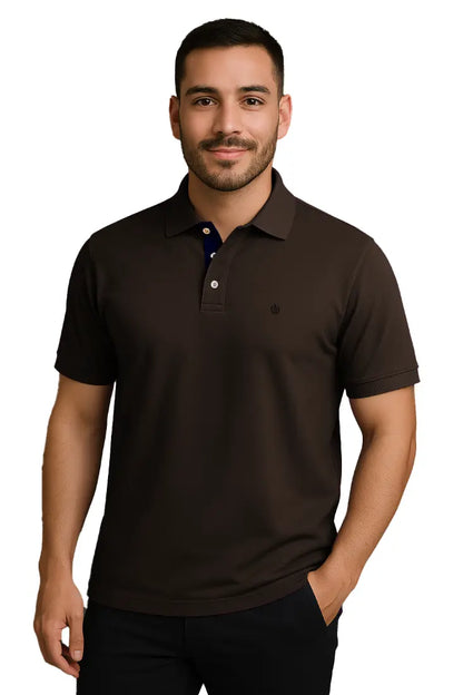 Hombre joven con barba vistiendo un polo de manga corta en color café chocolate profundo, con contraste azul marino en la carterita del cuello y escudo bordado, de la marca Dubrovnik