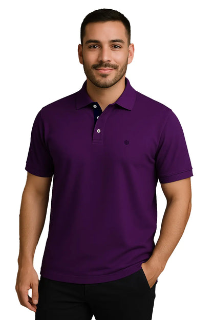 Hombre joven con barba vistiendo un polo de manga corta en color púrpura imperial, con detalle de carterita interna en color azul marino y logotipo de escudo bordado, de la marca Dubrovnik