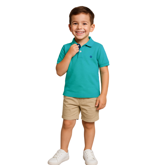 Niño sonriendo con un polo de manga corta en color verde turquesa, bermudas beige y zapatillas blancas, de la colección infantil de la marca Dubrovnik