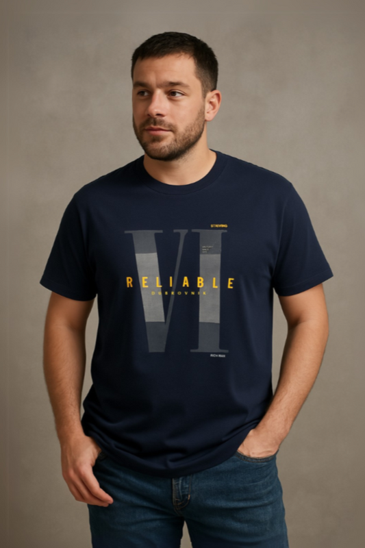 Hombre con barba corta vistiendo una playera azul marino de cuello redondo con el gráfico "RELIABLE" en amarillo y tipografía romana, de la colección urbana de Dubrovnik