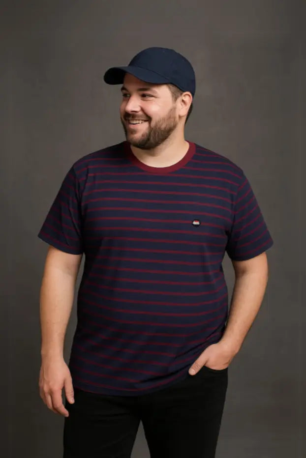 Hombre con barba y gorra azul marino vistiendo una playera de cuello redondo con diseño de rayas horizontales en azul marino y granate, de la colección Tallas Extras de Dubrovnik