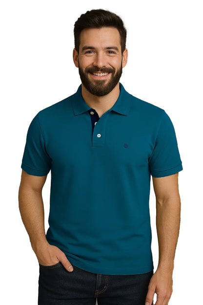 ombre con barba sonriendo con un polo de manga corta en color azul cerceta, con contraste azul marino en la carterita interna del cuello y logotipo bordado, de la marca Dubrovnik