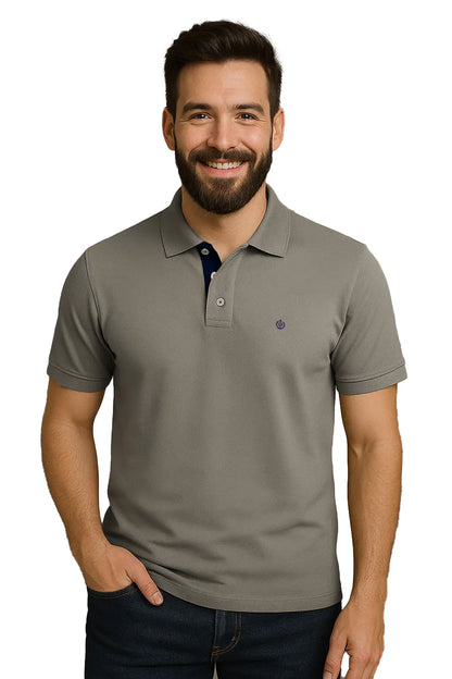 Hombre con barba sonriendo con un polo de manga corta en color gris cemento sólido, con contraste azul marino en la carterita interna del cuello y logotipo bordado, de la marca Dubrovnik