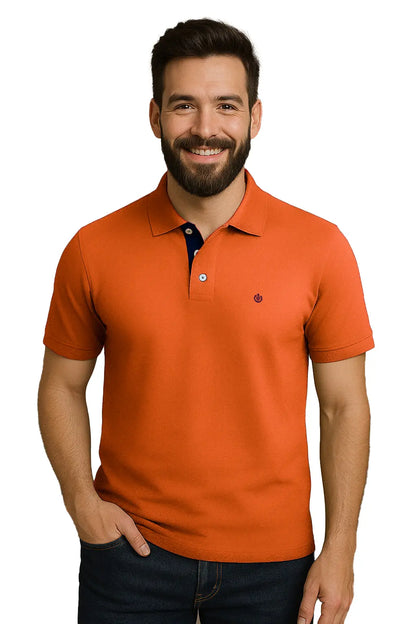 Hombre con barba sonriendo con un polo de manga corta en color naranja vibrante, con contraste azul marino en la carterita interna del cuello y logotipo de escudo bordado, de la marca Dubrovnik