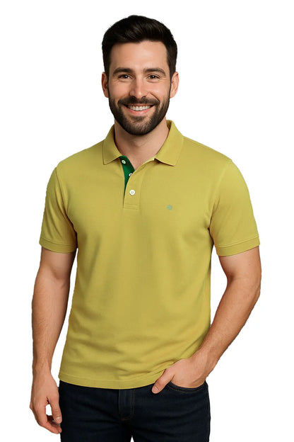 Hombre joven con barba sonriendo con un polo de manga corta en color verde lima suave, con contraste interno en verde bosque en la carterita del cuello y escudo bordado, de la marca Dubrovnik