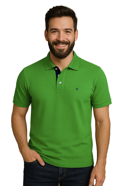 Hombre con barba sonriendo con un polo de manga corta en color verde trébol vibrante, con contraste azul marino en la carterita interna del cuello y escudo bordado, de la marca Dubrovnik