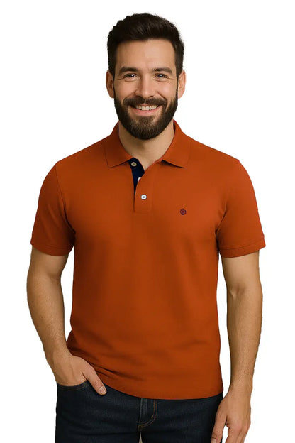Modelo sonriendo con polo Dubrovnik color teja de corte regular, resaltando el contraste azul marino en el interior del cuello y el escudo bordado circular