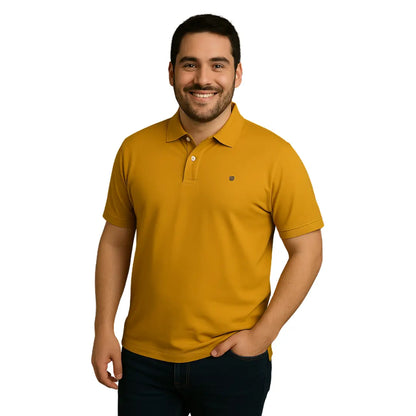 Modelo sonriendo con polo Dubrovnik color mostaza de corte regular y ajuste moderno, confeccionado en mezcla 50/50 algodón-poliéster con logotipo bordado en el pecho