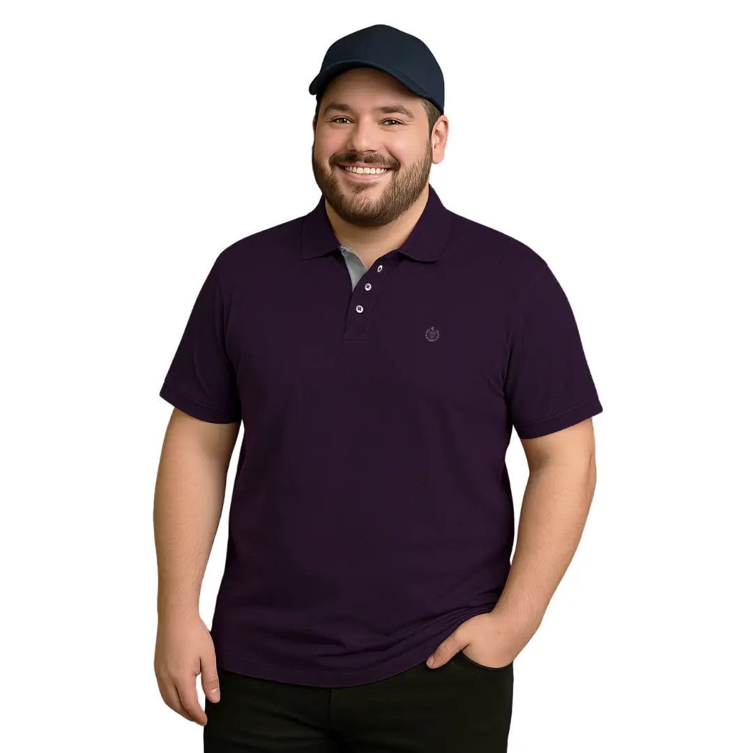 Hombre de complexión robusta sonriendo con polo color morado imperial y gorra tipo baseball azul marino, resaltando el detalle interno del cuello en gris claro y logotipo bordado, de la marca Dubrovnik