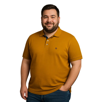 Hombre con barba de complexión robusta sonriendo con un polo de manga corta en color amarillo mostaza, con detalle de carterita interna en azul marino y logotipo bordado, de la marca Dubrovnik