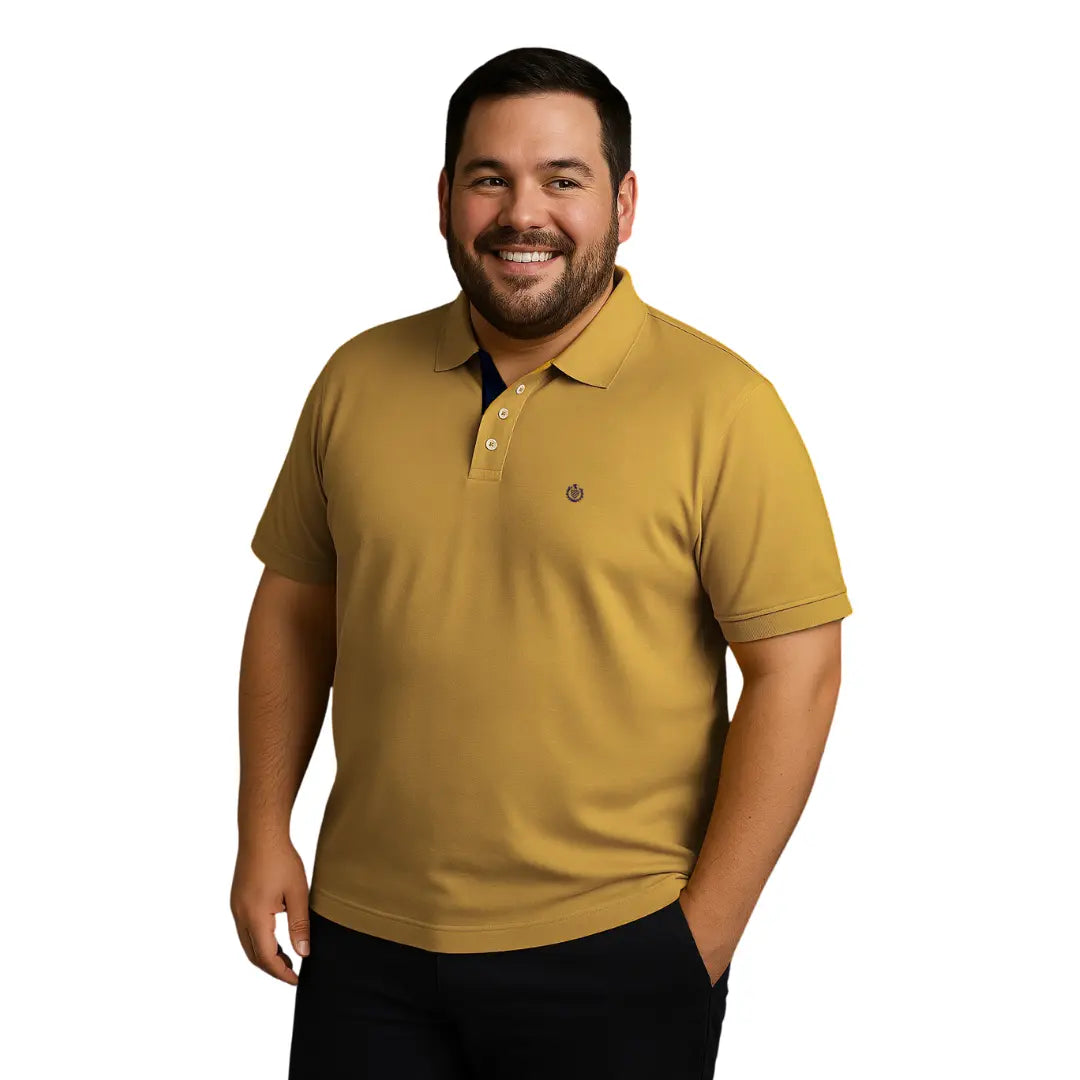 Hombre de complexión robusta sonriendo con un polo Dubrovnik color mostaza, destacando el contraste azul marino en la carterita del cuello y logotipo bordado, disponible en tallas S a 5XL