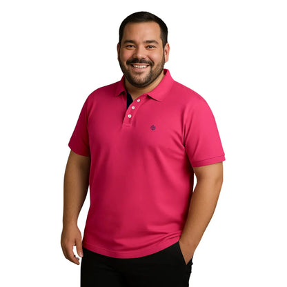 Hombre de complexión robusta sonriendo con polo Dubrovnik color rosa fucsia vibrante en talla extra, con carterita interna en contraste azul marino y botones blancos.