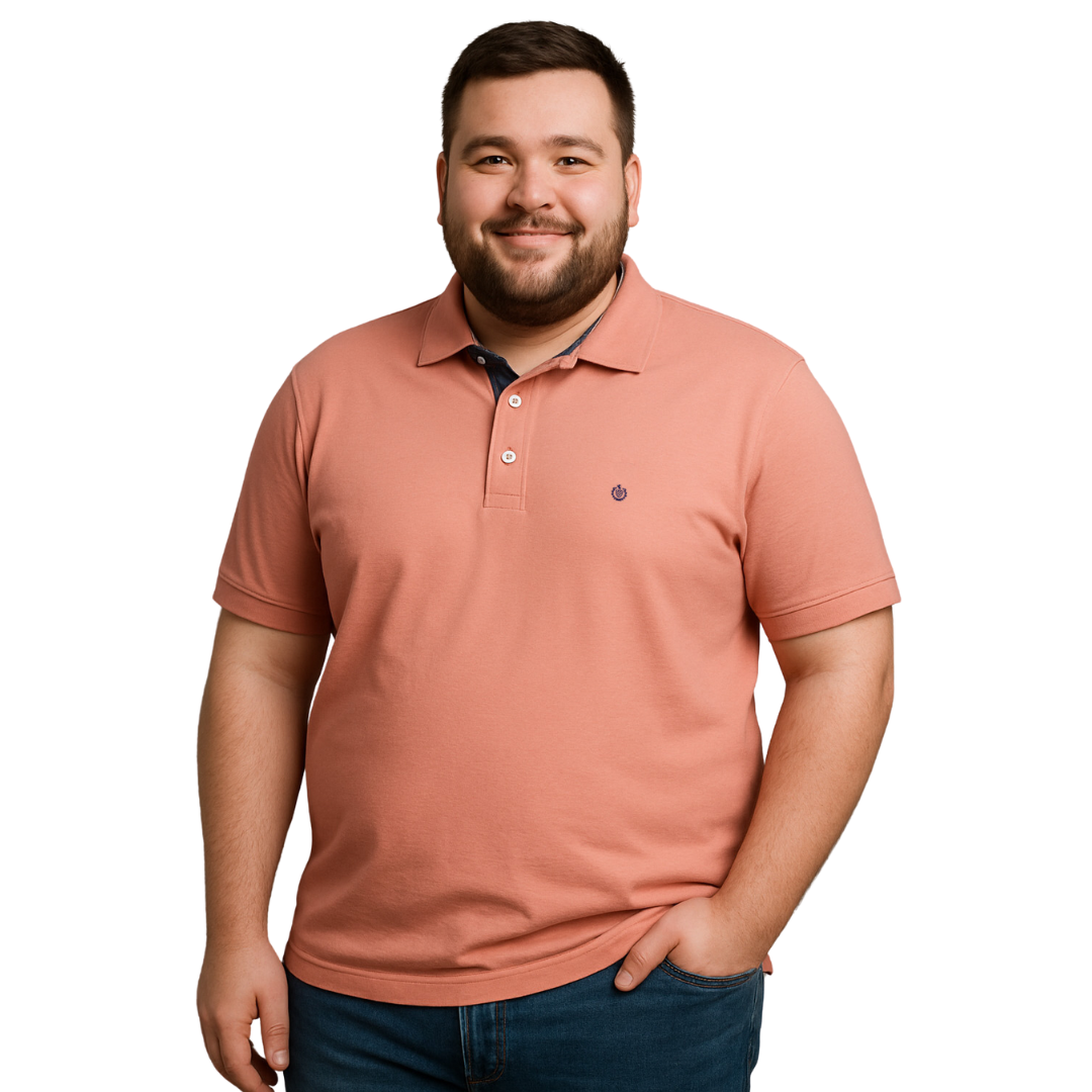 Hombre de complexión robusta sonriendo con polo Dubrovnik color salmón de la línea Tallas Extras, destacando el contraste azul marino en el cuello interno y logotipo bordado